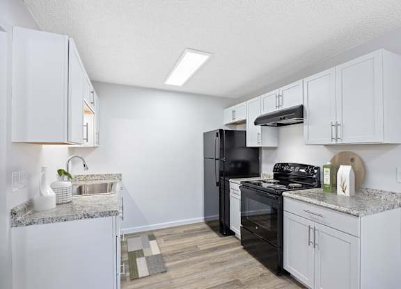 A kitchen with white cabinets and a black refrigerator.
