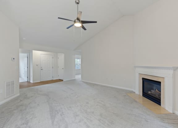 an empty living room with a fireplace and a ceiling fan at Four Bridges, Liberty Township, Ohio