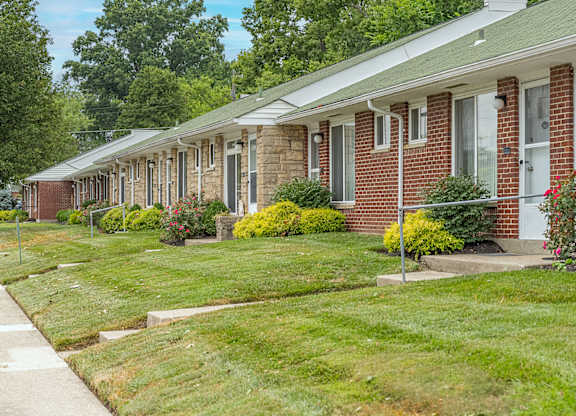 A row of houses with green lawns and trees in the background.