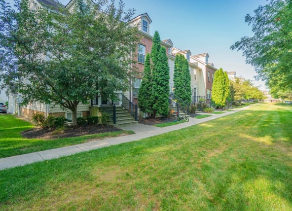 exterior view of a brick apartment building with green grass and trees at Traditions at Slate Ridge, Reynoldsburg Ohio
