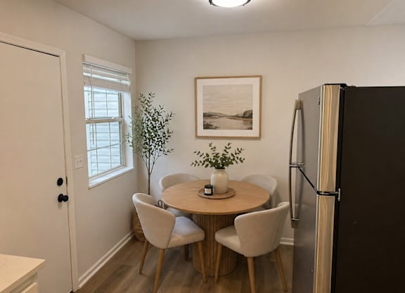 A kitchen with a table and chairs and a fridge.