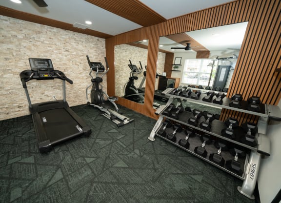 Gym with a treadmill and weights on the wall and a mirror at Honey Creek, Greenwood, IN, 46143
