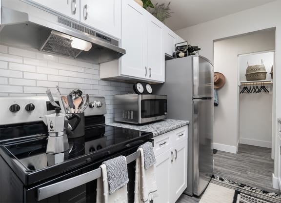 a kitchen with stainless steel appliances and white cabinets at The Heights Apartments, Cincinnati, Ohio