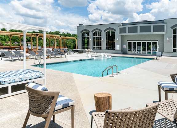 a swimming pool with chairs and a building in the background at The Heights Apartments, Cincinnati, OH, 45220
