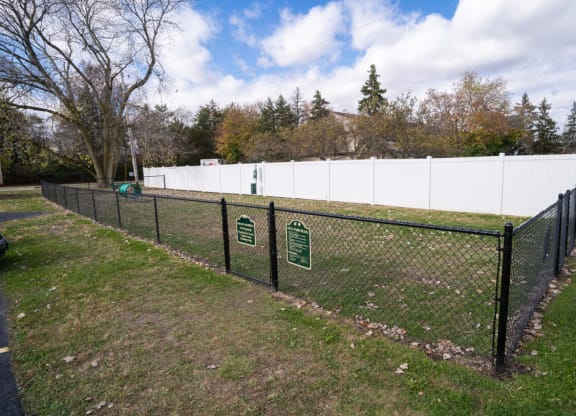 a chain link fence with two signs on it in a field