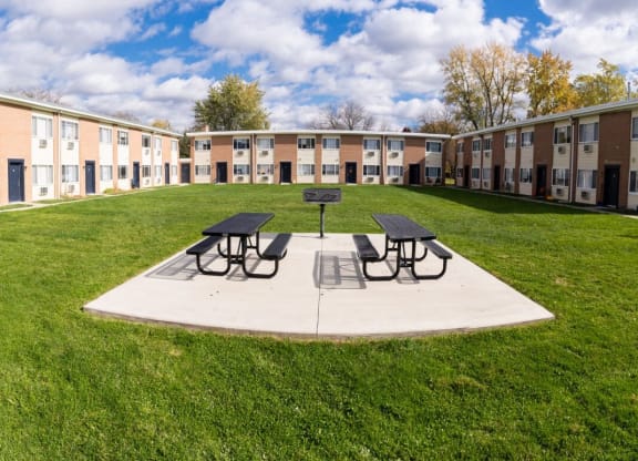 a courtyard with picnic tables in front of an apartment building