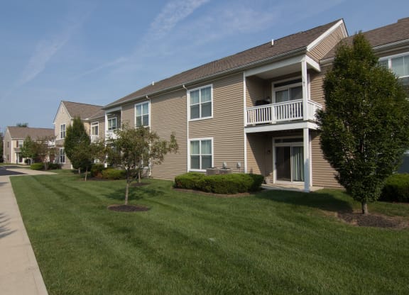 a grassy area with trees and bushes in front of a building  at Grove City Summit, Grove City, OH