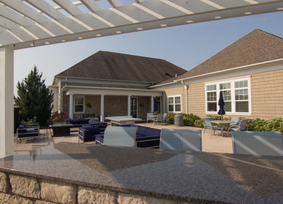 an outdoor entertaining area with a stone wall and a white pergola  at Grove City Summit, Grove City