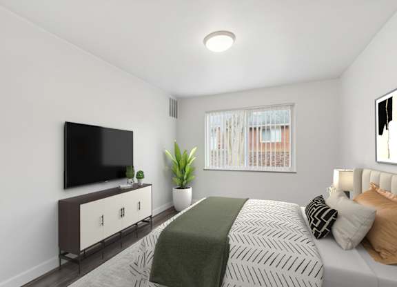 A bedroom with a bed, a television, and a plant.
