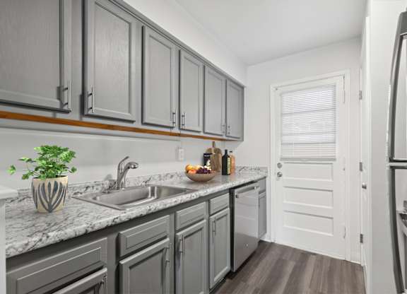A kitchen with a marble countertop and grey cabinets.