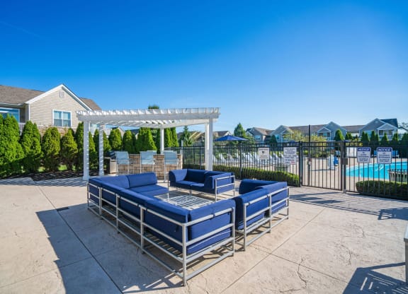 the lounge area of a pool with blue couches and a white pergola at Grove City Summit Apartments, Grove City, 43123