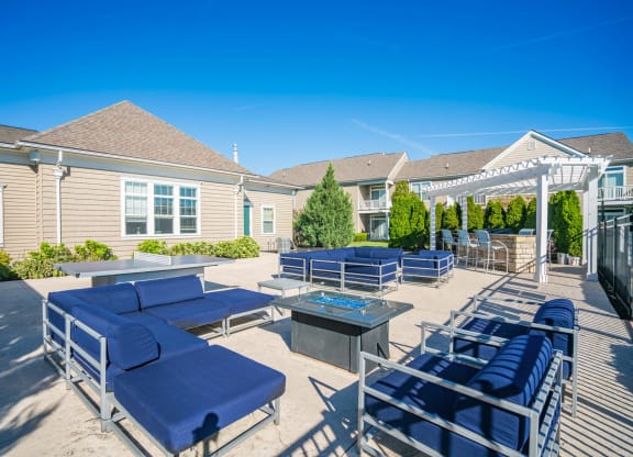 the clubhouse patio with blue lounge chairs and tables and a fire pit at Grove City Summit Apartments, Grove City, OH