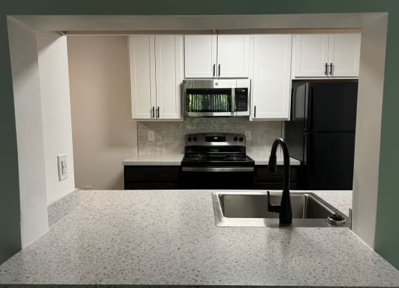 Kitchen with white cabinets and black appliances and a sink  at Hilltop Apartments, Cincinnati, Ohio, 45213-2638