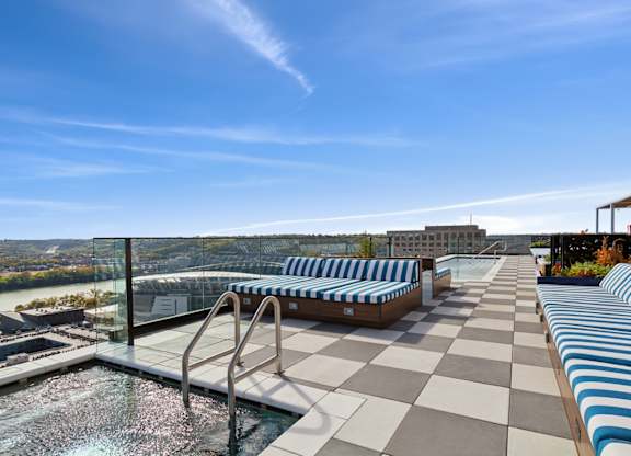A rooftop pool area with blue and white striped sun loungers.