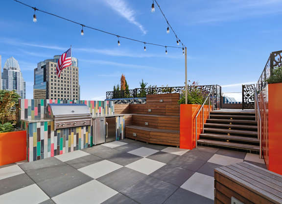 A rooftop patio with a grill and a view of the city.