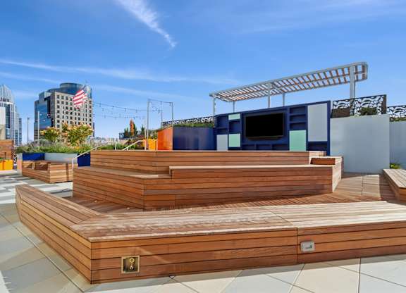 A wooden deck with a TV on top and a city skyline in the background.