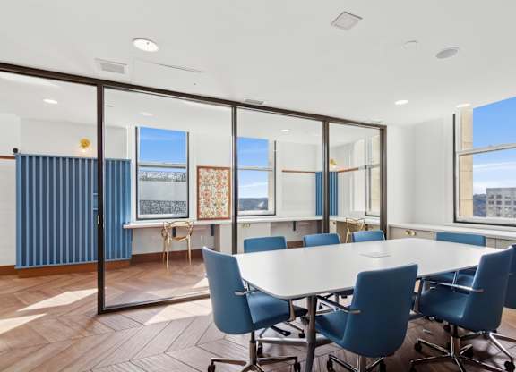 A conference room with a long table and blue chairs.