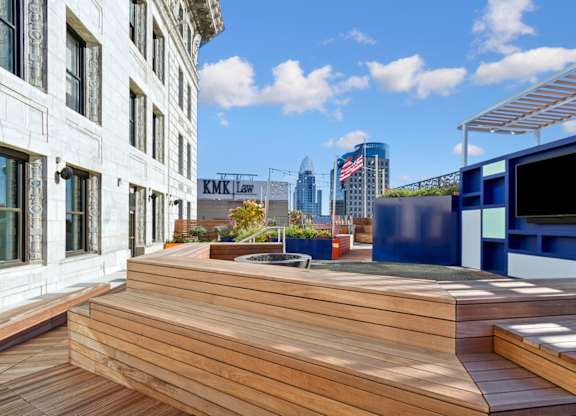 A wooden deck with a TV on the side and a building in the background.