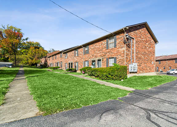 A red brick building with a green lawn in front.