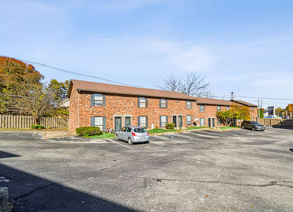 A parking lot with a building in the background and a car parked in the lot.