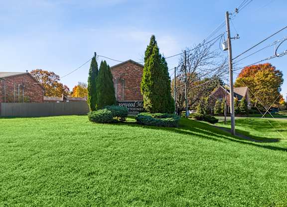 A green lawn in front of a brick building with a sign that says