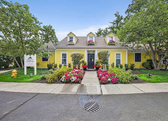 A yellow house with a white sign in front of it.