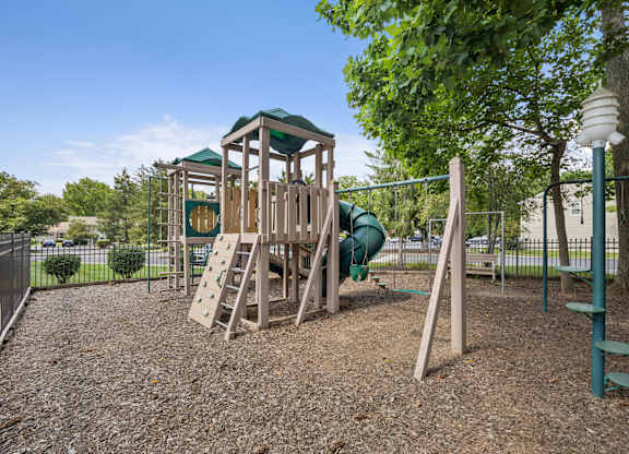 A playground with a wooden swing set and a green slide.