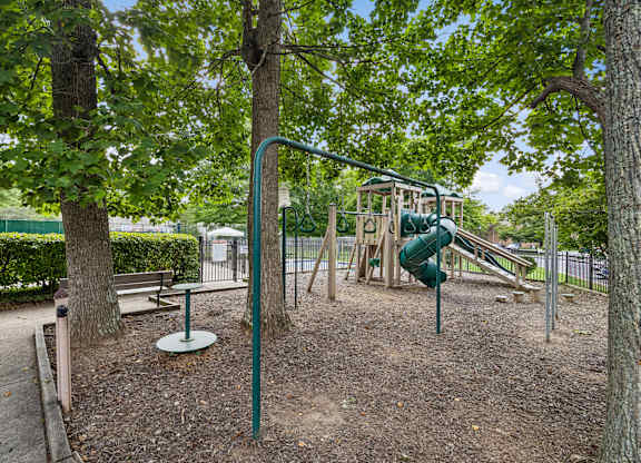 A playground with a green slide and a swing set.