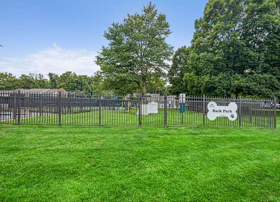 A sign that says Bark Park is in front of a fence.