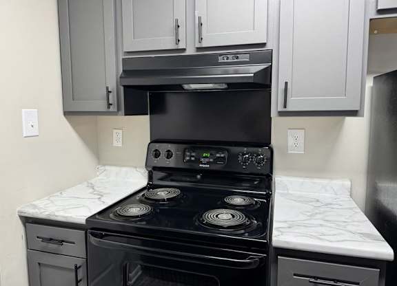 A modern kitchen with a black stove top oven and white cabinets at Quail Run Apartments, Indiana
