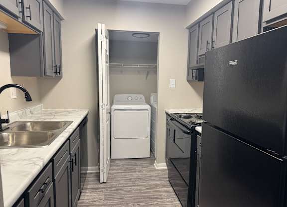 A black refrigerator is on the right side of a kitchen at Quail Run Apartments, Columbus, 47201