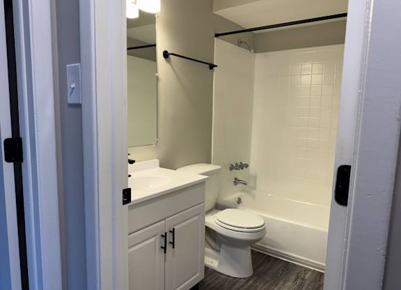A white toilet is in a bathroom with a white sink and a white bathtub at Quail Run Apartments, Columbus, Indiana