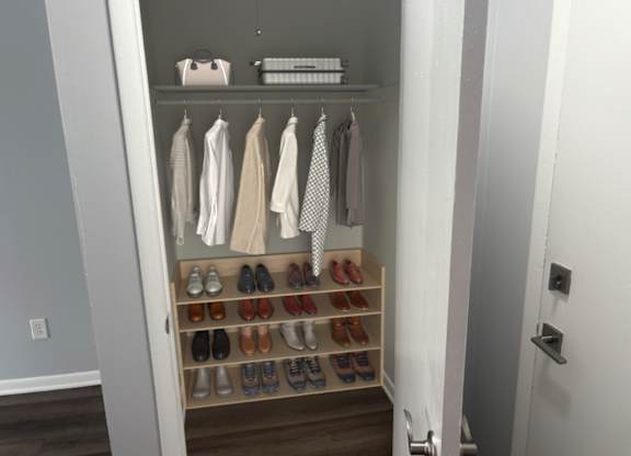 A white closet with clothes and shoes.