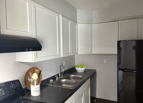 A kitchen with black appliances and white cabinets.