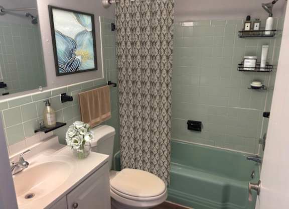 A bathroom with a toilet, sink, and shower.