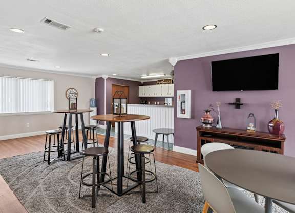 A room with a purple wall and a black television mounted on it.