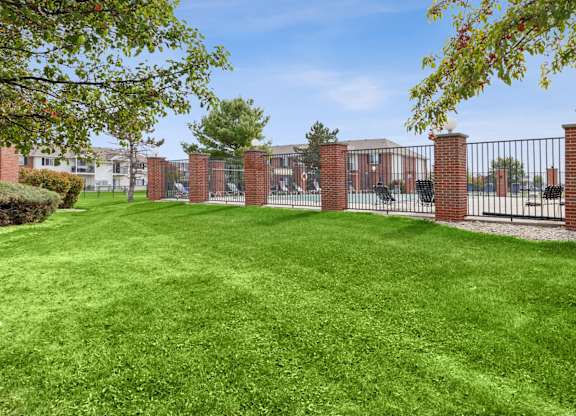 A green lawn with a fence and a building in the background.