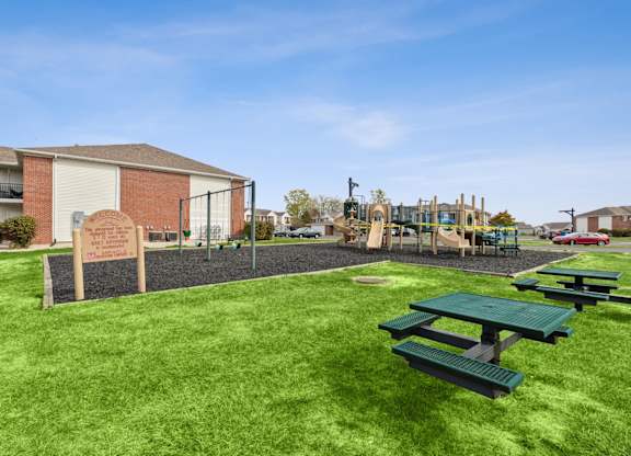 Picnic tables are set up on a green lawn.