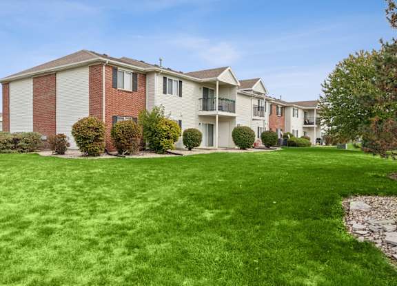 A row of apartment buildings with green lawns in front.