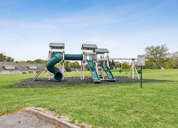 A playground with a green slide and a white sign.