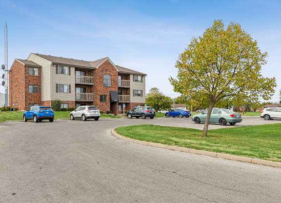 A large apartment building with cars parked in front.