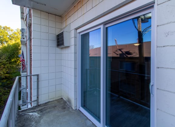 a balcony with a large glass door and a white tile wall