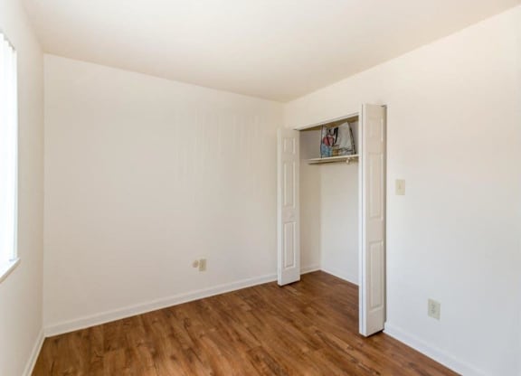 the living room of an empty house with a wooden floor and white walls at Quail Run Apartments, Columbus, 47201