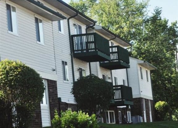 a white house with a balcony on a lawn at Quail Run Apartments, Columbus, IN
