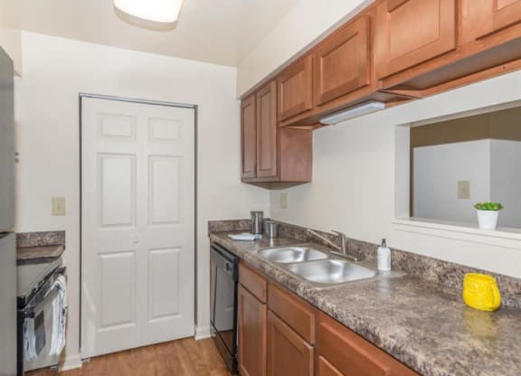 a kitchen with wood cabinets and granite counter tops and a sink at Quail Run Apartments, Indiana