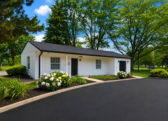 A white house with a black roof and a driveway in front.