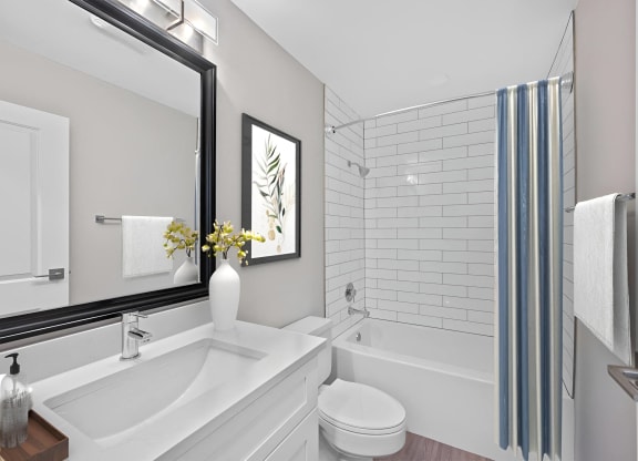 a white bathroom with a large mirror and a tub and a sink at Indian Creek Apartments*, Cincinnati, OH