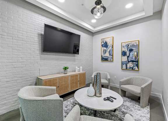 Luxury Apartments in West Chester, OH, With In-Unit Washer and Dryer - Liberty Center - A Resident Lounge Area with Plush Seating, a Plush Rug, a Round Table, and a Wall-Mounted TV