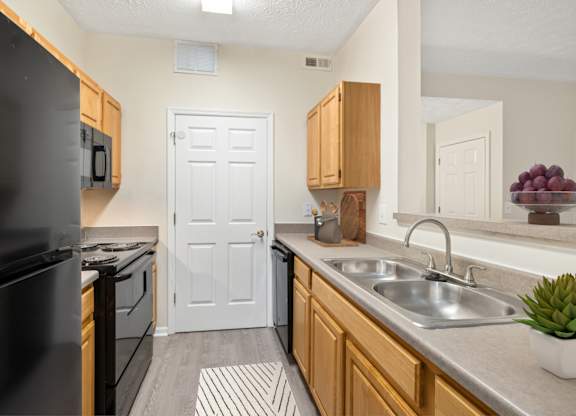 A kitchen with a black refrigerator and wooden cabinets.