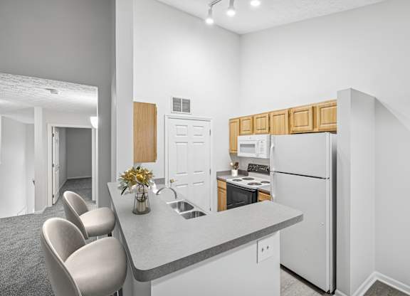 A kitchen with a white refrigerator and a grey counter top.